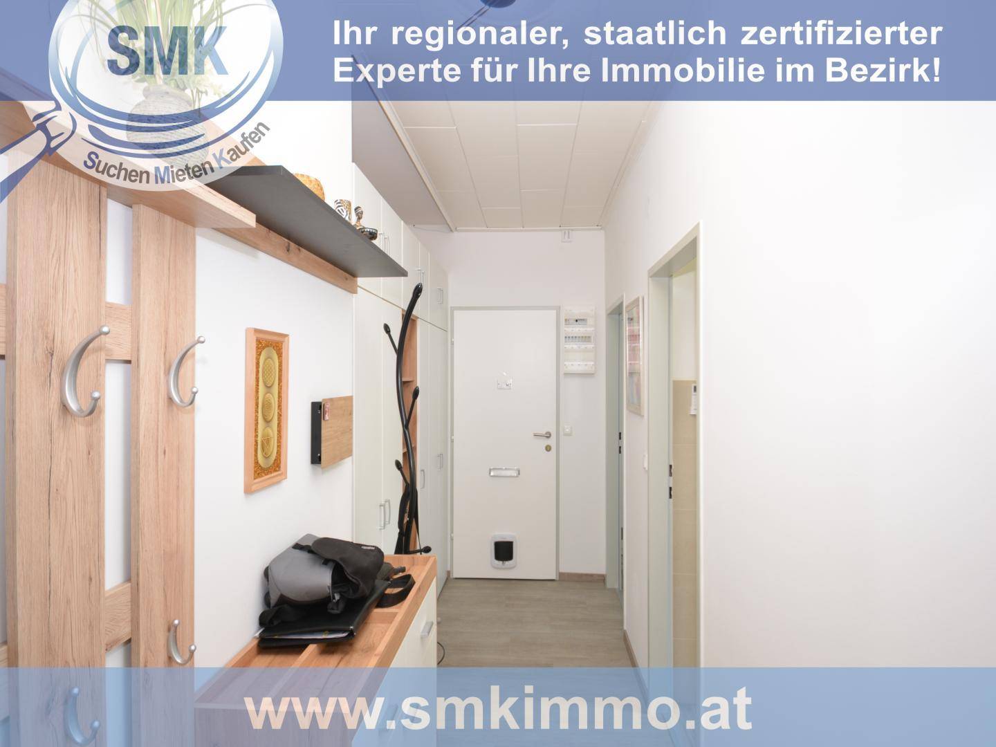 Heller Flur mit Garderobe aus Holz und weiß gestrichenen Wänden, einladend gestaltet.