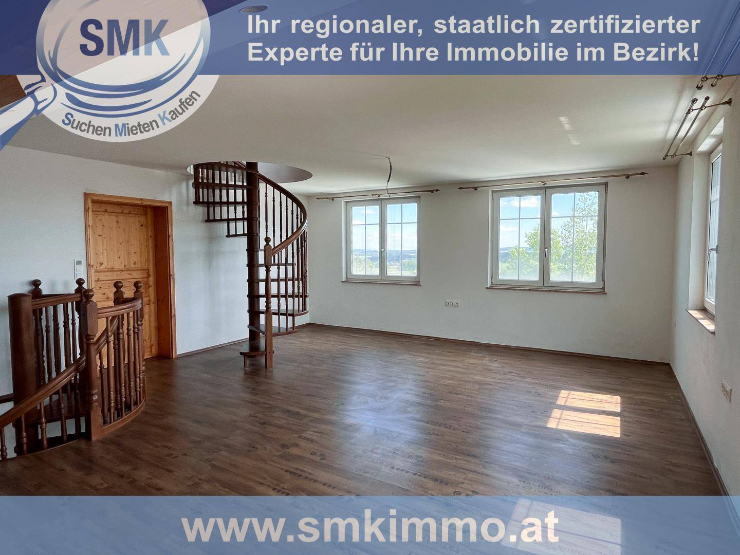 Geräumiger, heller Raum mit Holzboden, Wendeltreppe und weitem Ausblick durch die Fenster.