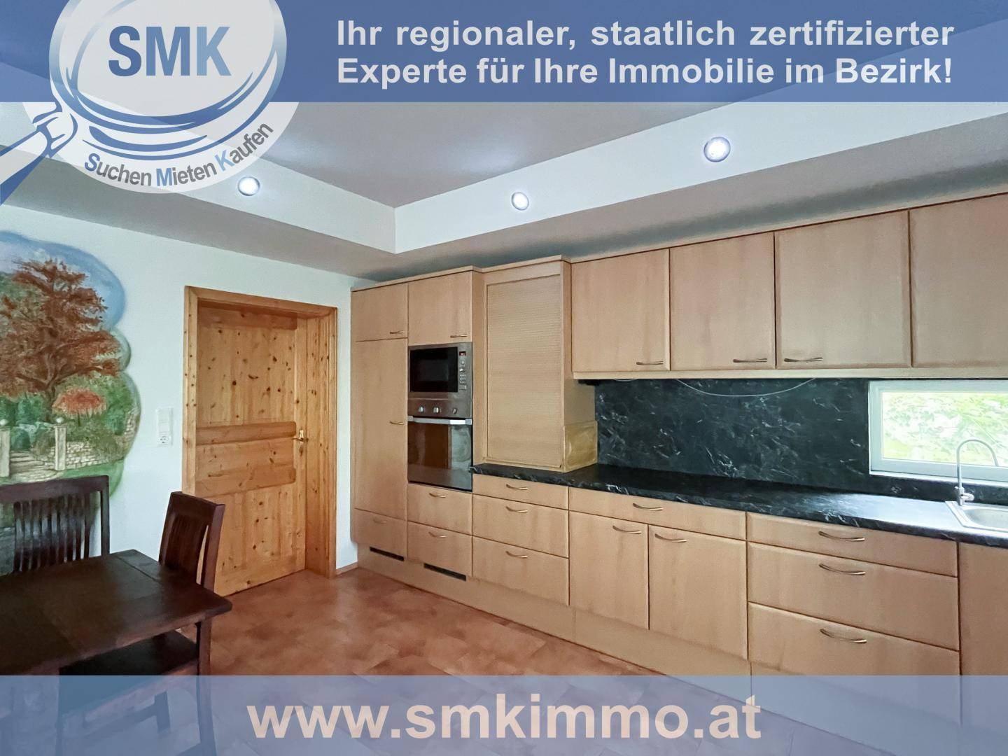 Helle Holzküche mit Einbaugeräten, dunkler Arbeitsplatte und Fenster.