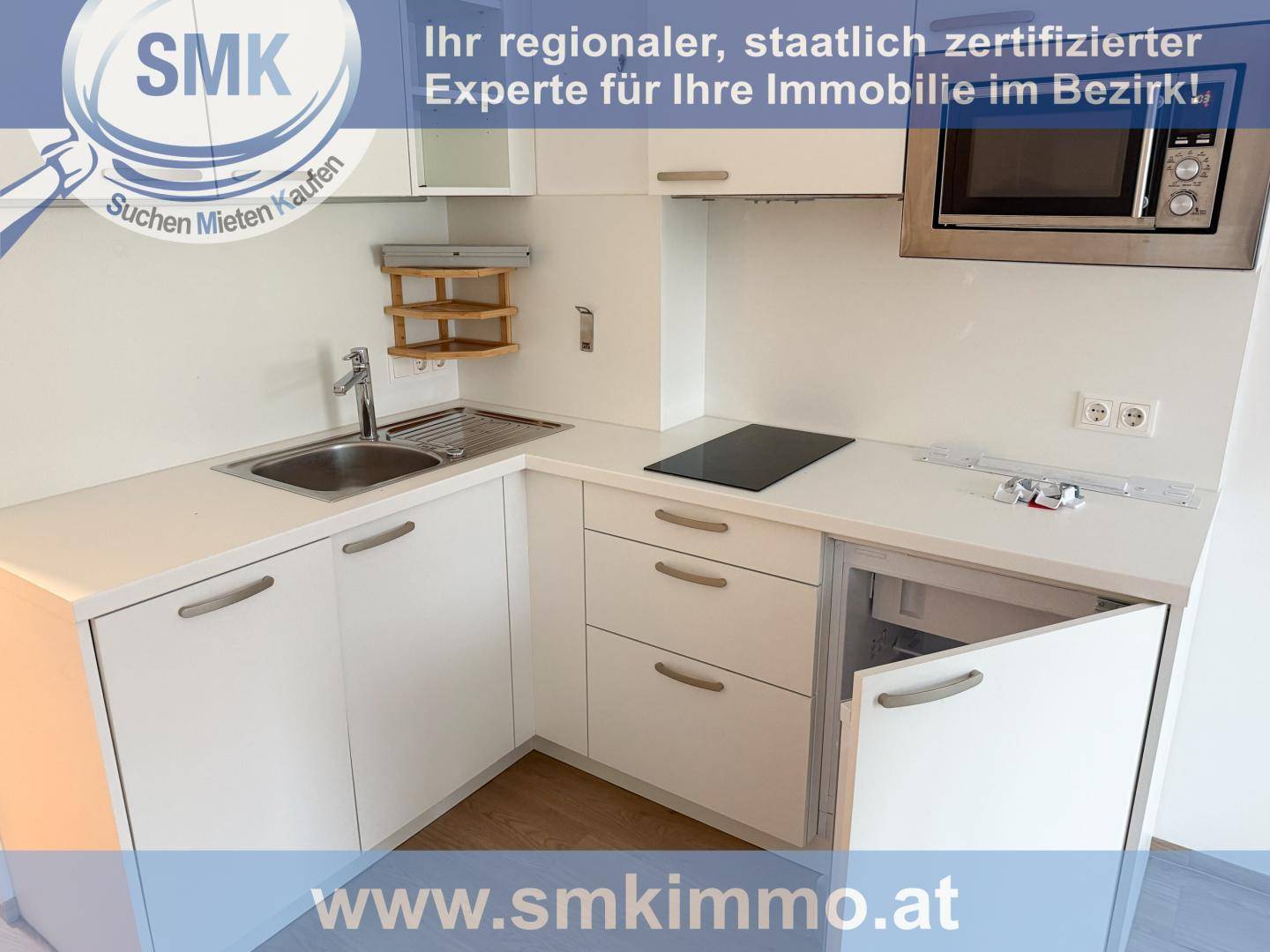 Moderne Küchenzeile mit weißen Schränken, Spüle, Induktionskochfeld und integrierter Mikrowelle.