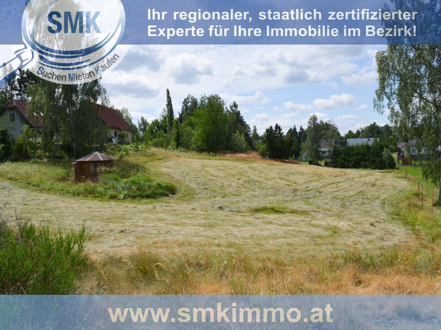 Ländliche Szene mit einem weiten Feld, einem Holzpavillon und Häusern in der Ferne.