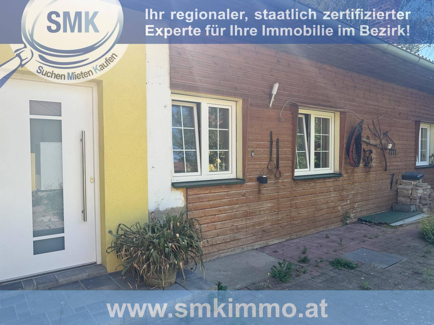 Fassade eines Hauses mit Holzverkleidung, weißen Fenstern und einer modernen Eingangstür.