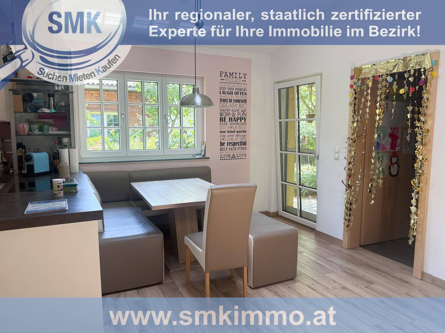 Helle Küche mit integriertem Essbereich, großem Fenster und Zugang zu einem weiteren Raum.