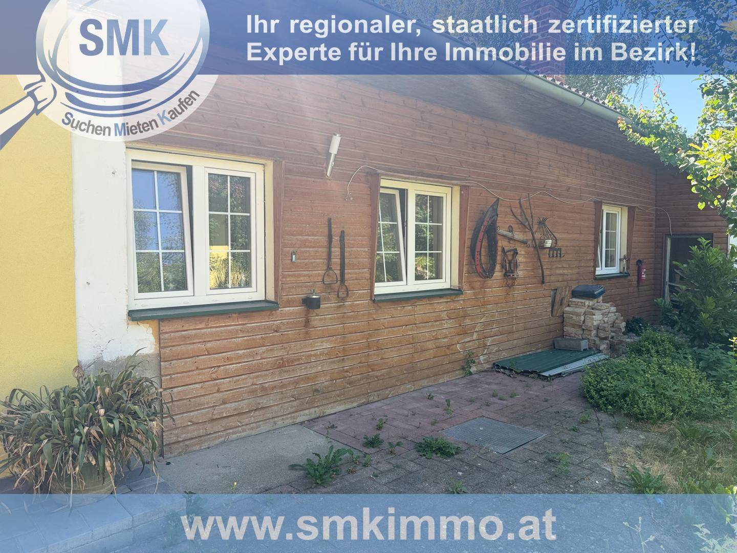 Rustikales Holzhaus mit traditioneller Fassade und mehreren Fenstern, umgeben von Grün.