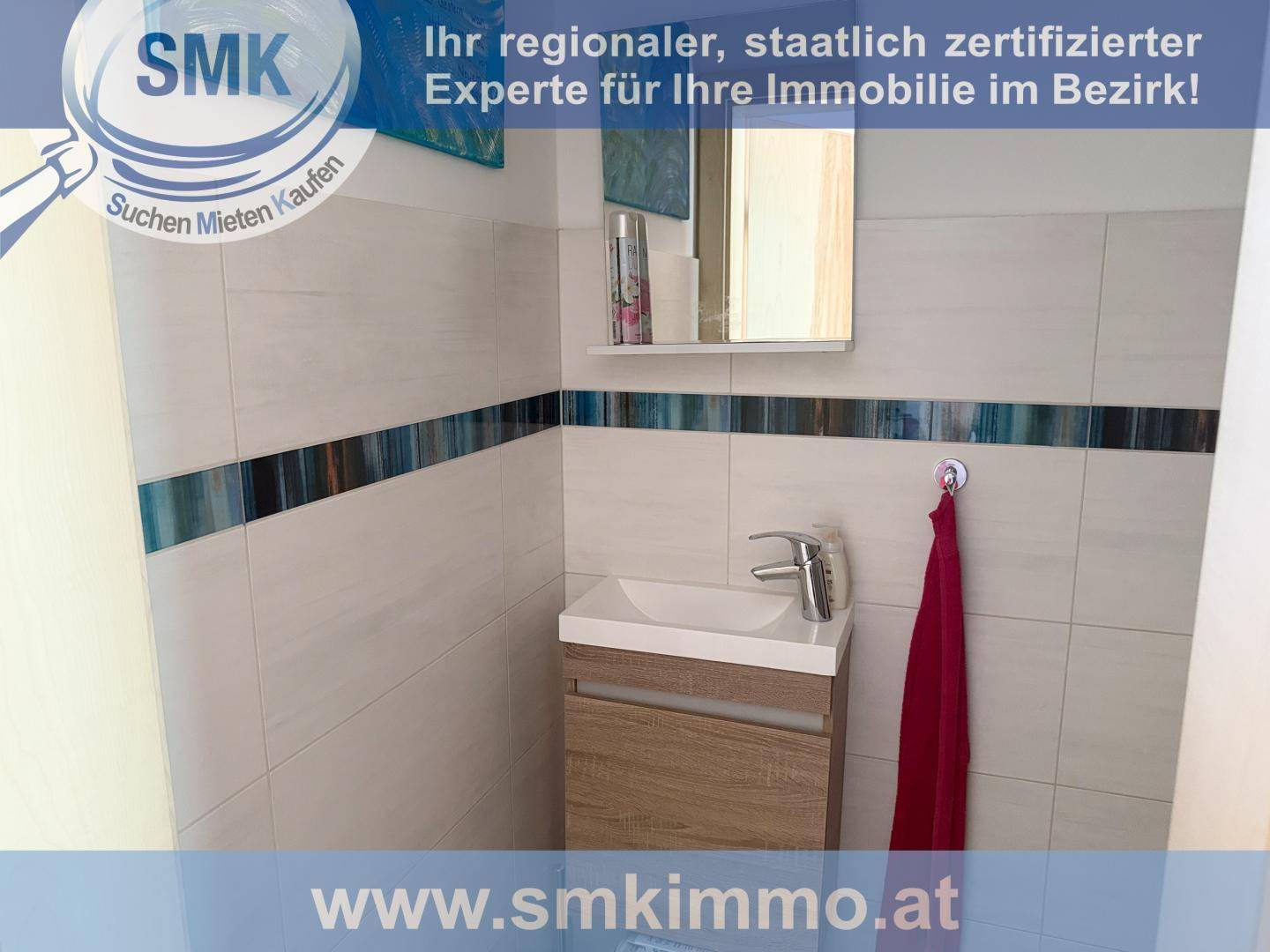 Kleines Badezimmer oder Gäste-WC mit modernem Waschbecken und Wandfliesen in Weiß und Blau.