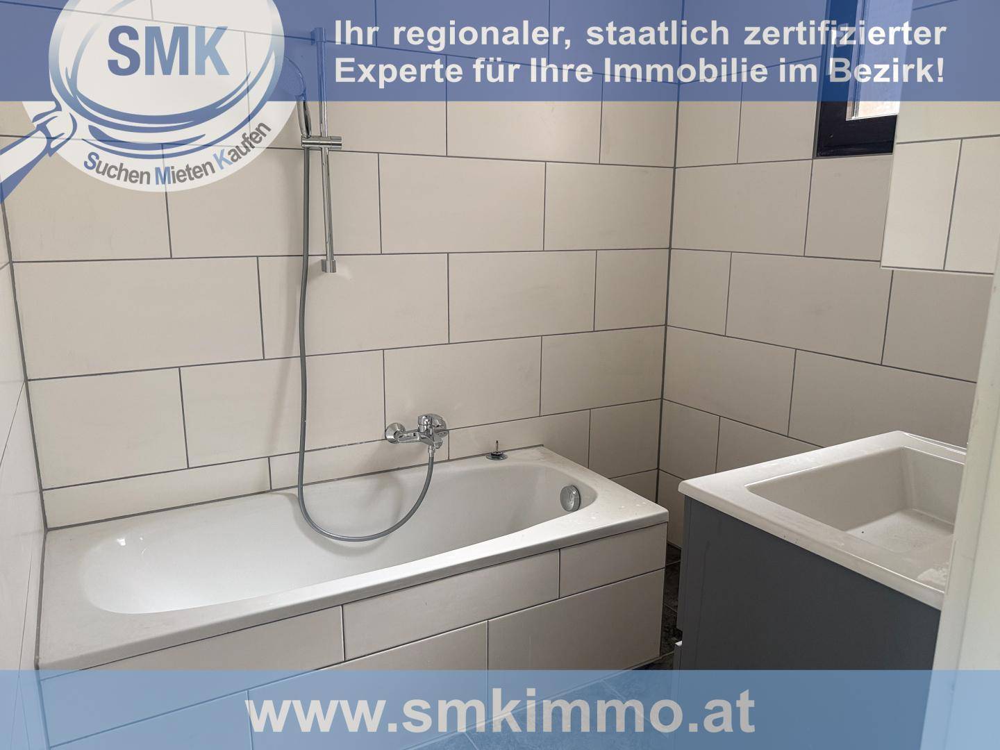 Helles Badezimmer mit Badewanne und modernem Waschbecken, komplett gefliest in Weiß.