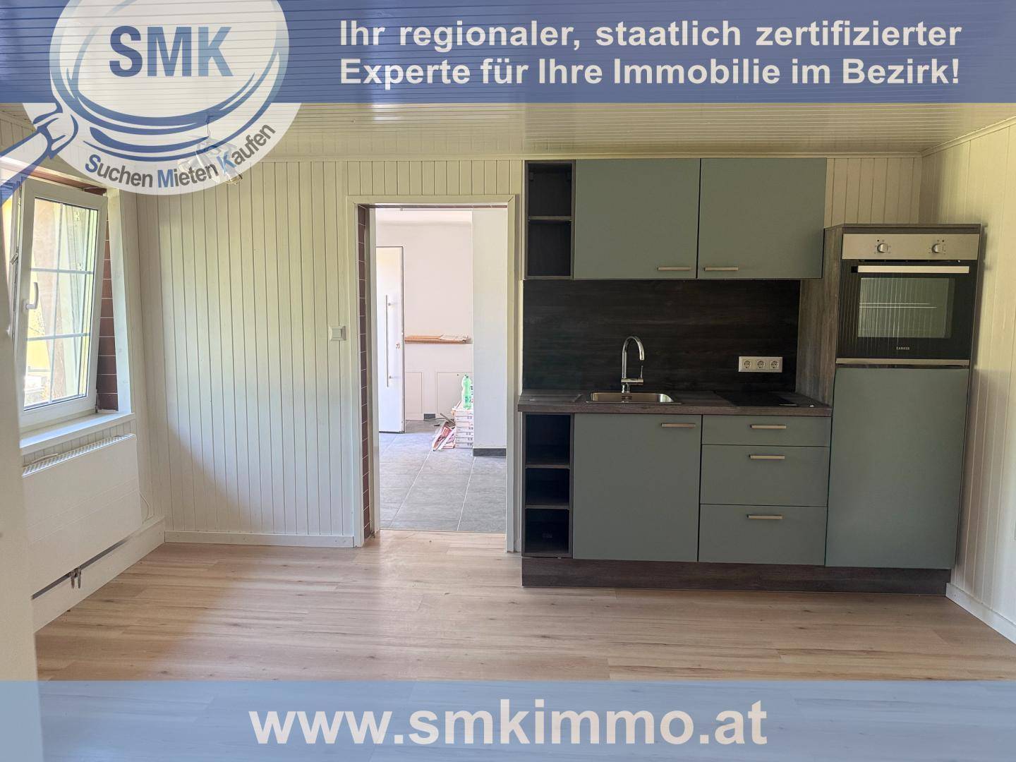 Funktionale Küchenzeile mit grauen Fronten und Blick in einen angrenzenden Raum, ideal für kleine Wohnungen.