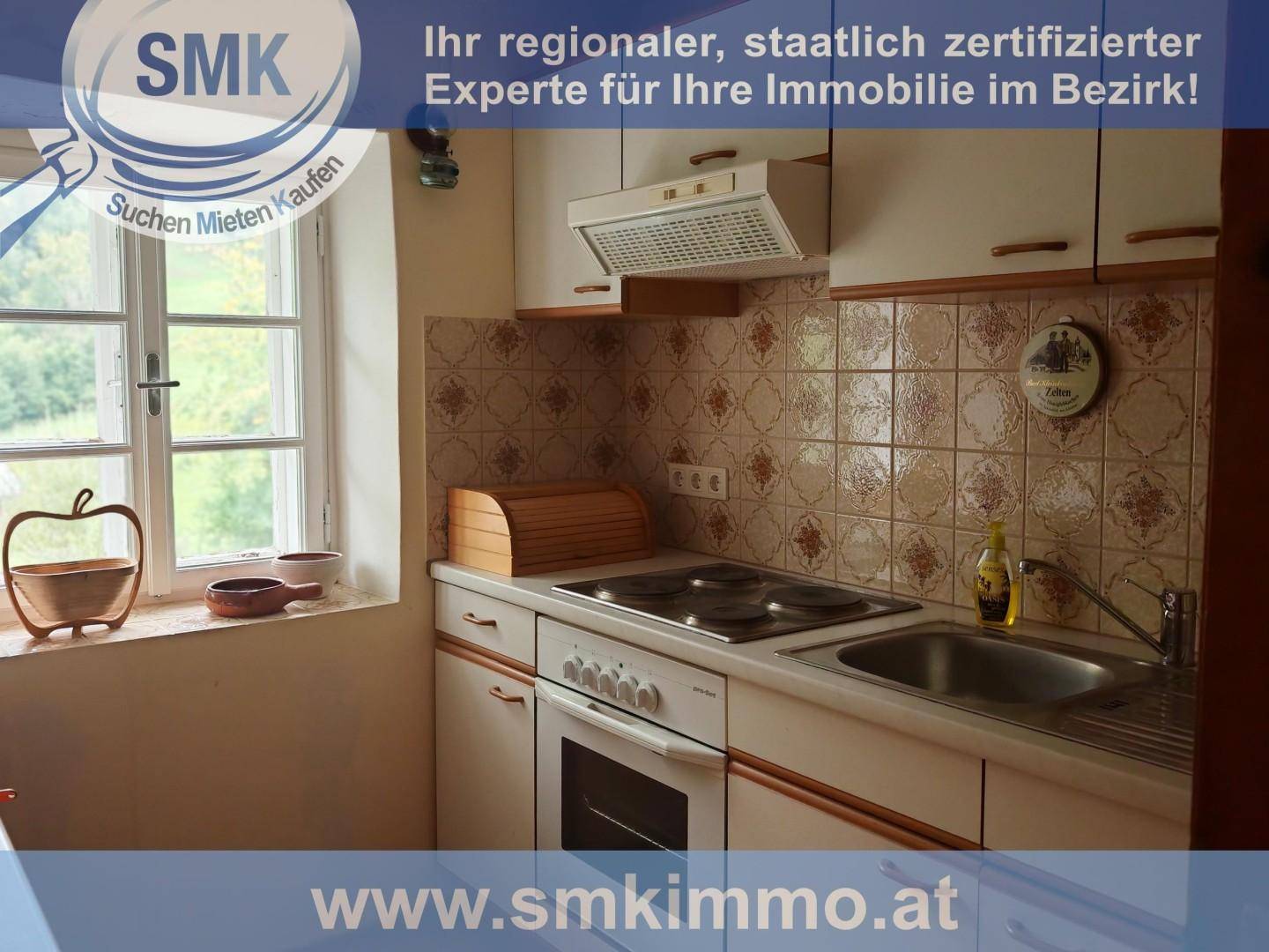 Kleine Küche mit traditionellen Fliesen, Elektroherd und Spüle, hell durch ein Fenster.