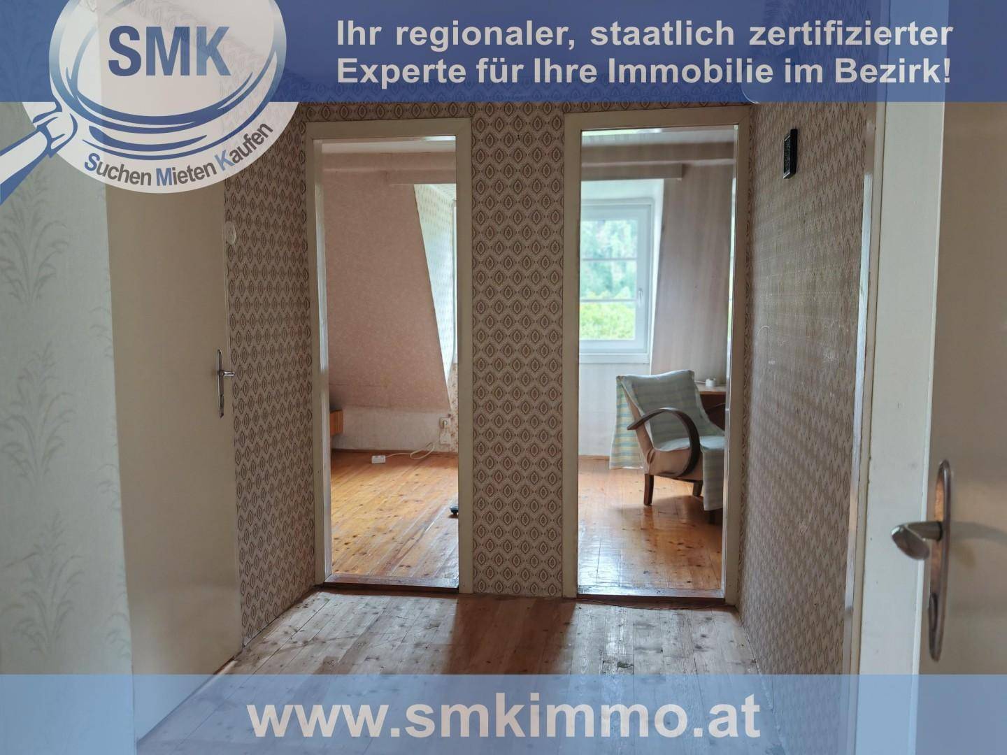 Flur mit Holzboden und zwei Türen, die zu weiteren Räumen mit Dachschrägen führen.