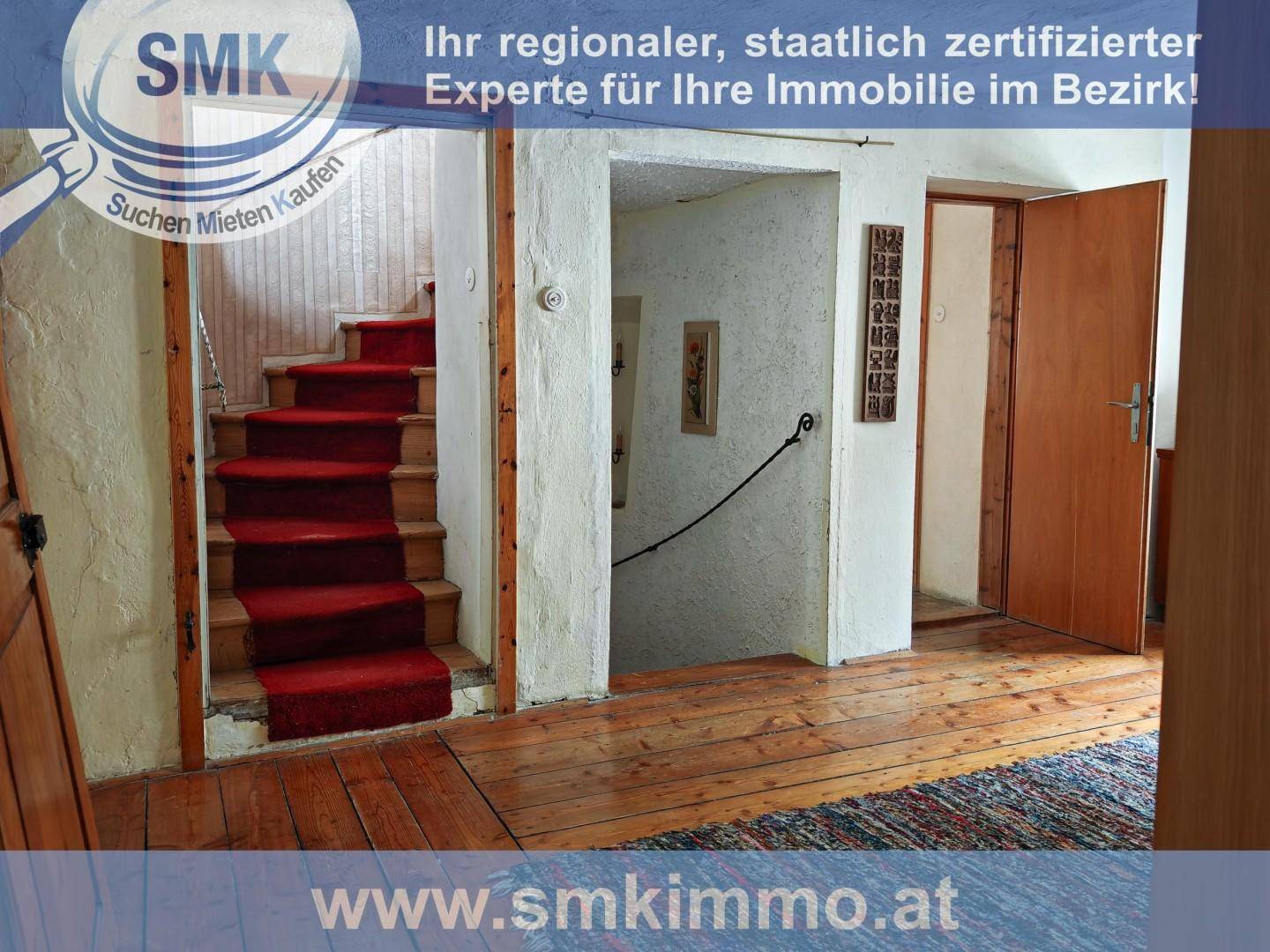 Geräumiger Flur mit Holztreppe und rotem Teppich, der in die oberen Stockwerke führt.