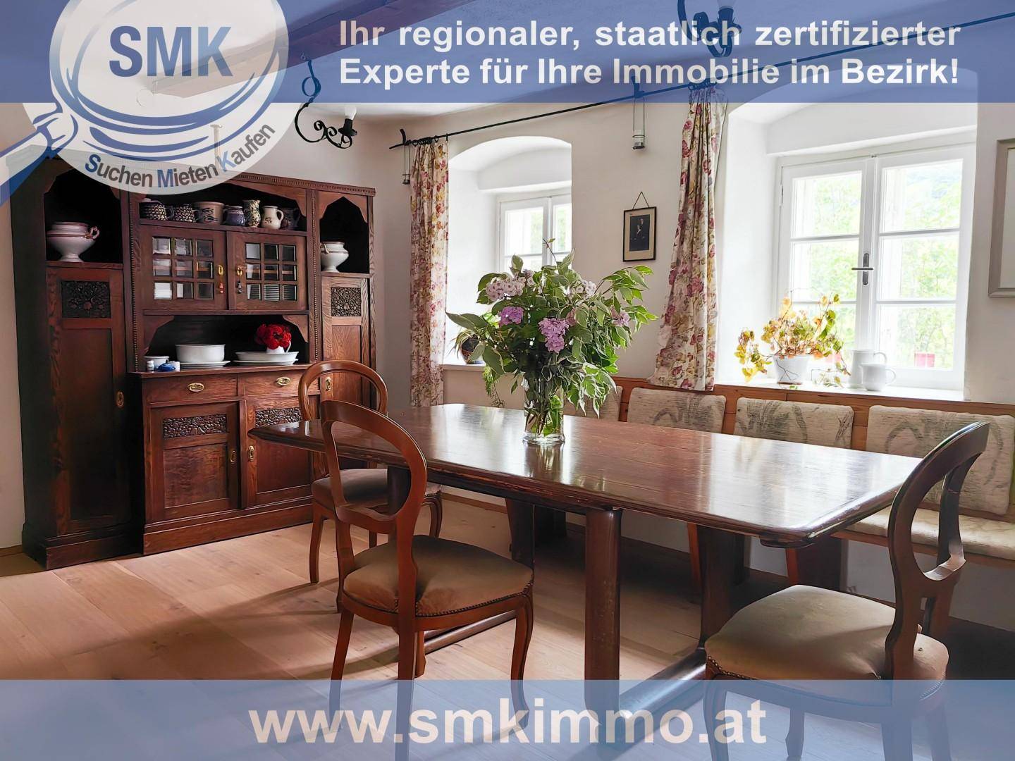 Gemütlicher Essbereich mit Holztisch, Stühlen und einem antiken Schrank, beleuchtet durch Fenster.