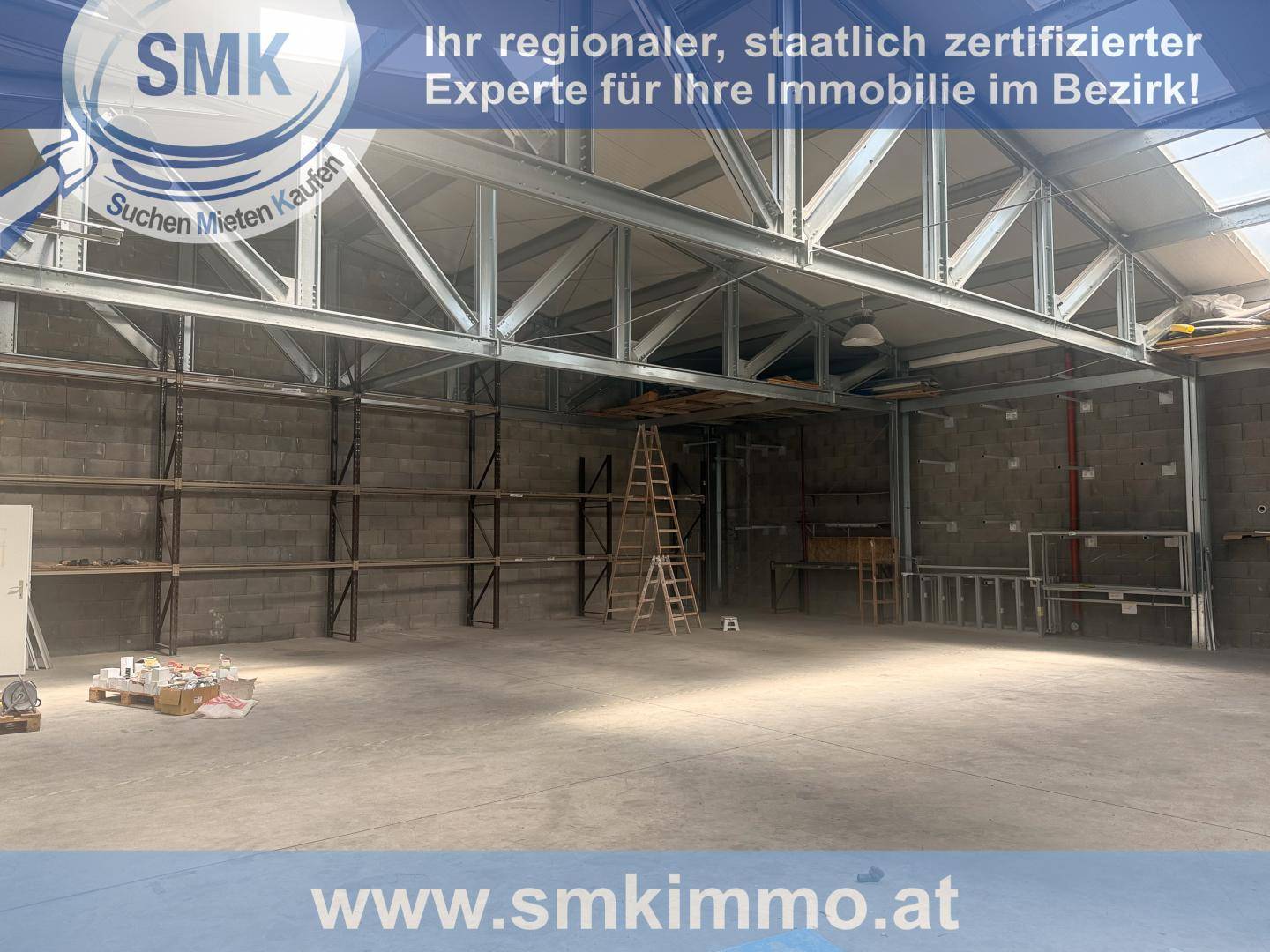 Innenansicht einer großen Lagerhalle mit hohen Decken, Metallträgern und Regalsystemen an den Wänden.