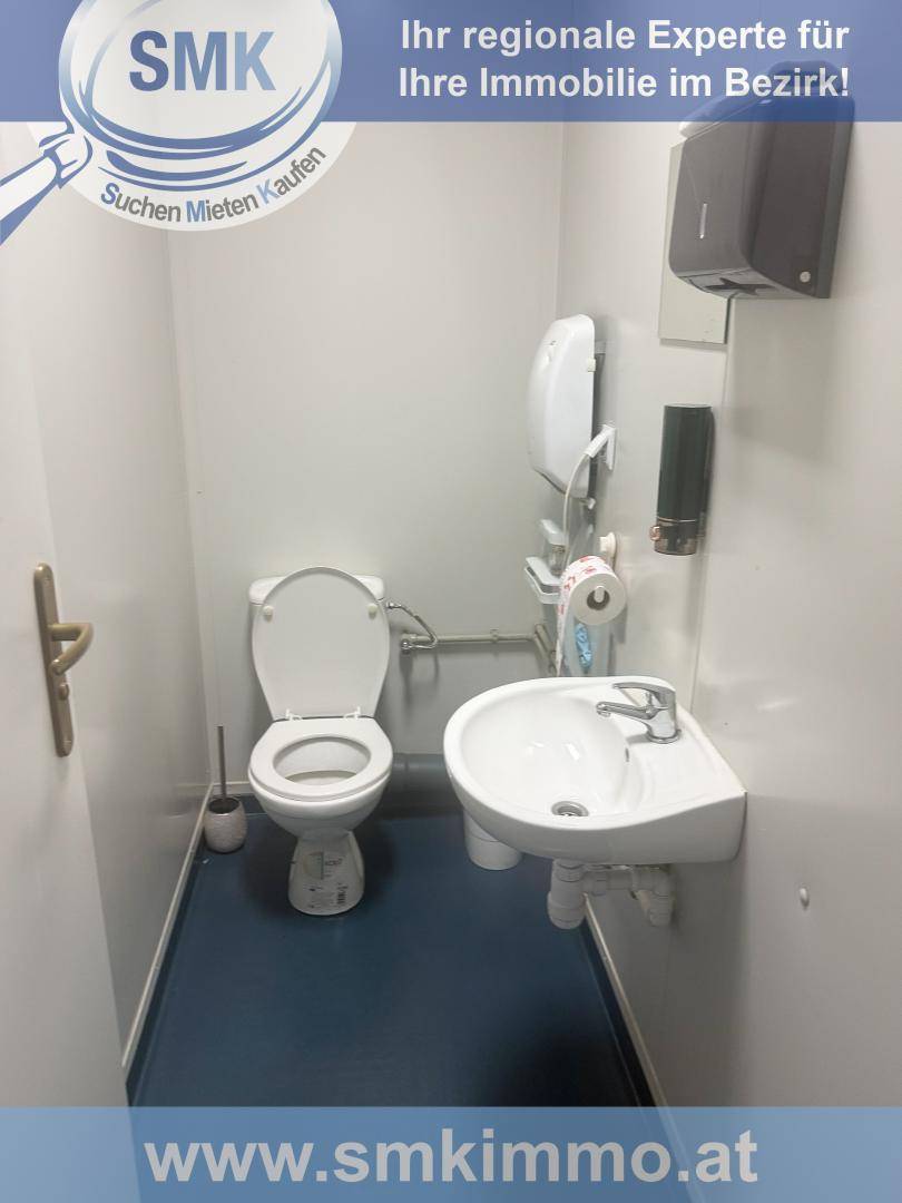 Kleiner Toilettenraum mit WC, Waschbecken und blauem Bodenbelag.