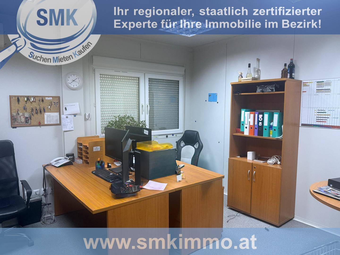 Möbliertes Büro mit großem Schreibtisch, Computern, Bürostühlen und einem Bücherregal.