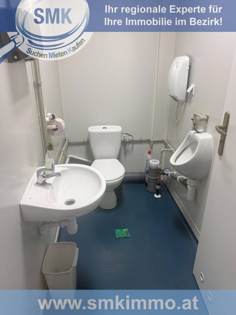 Kleiner Toilettenraum mit WC, Waschbecken, Urinal und blauem Bodenbelag.