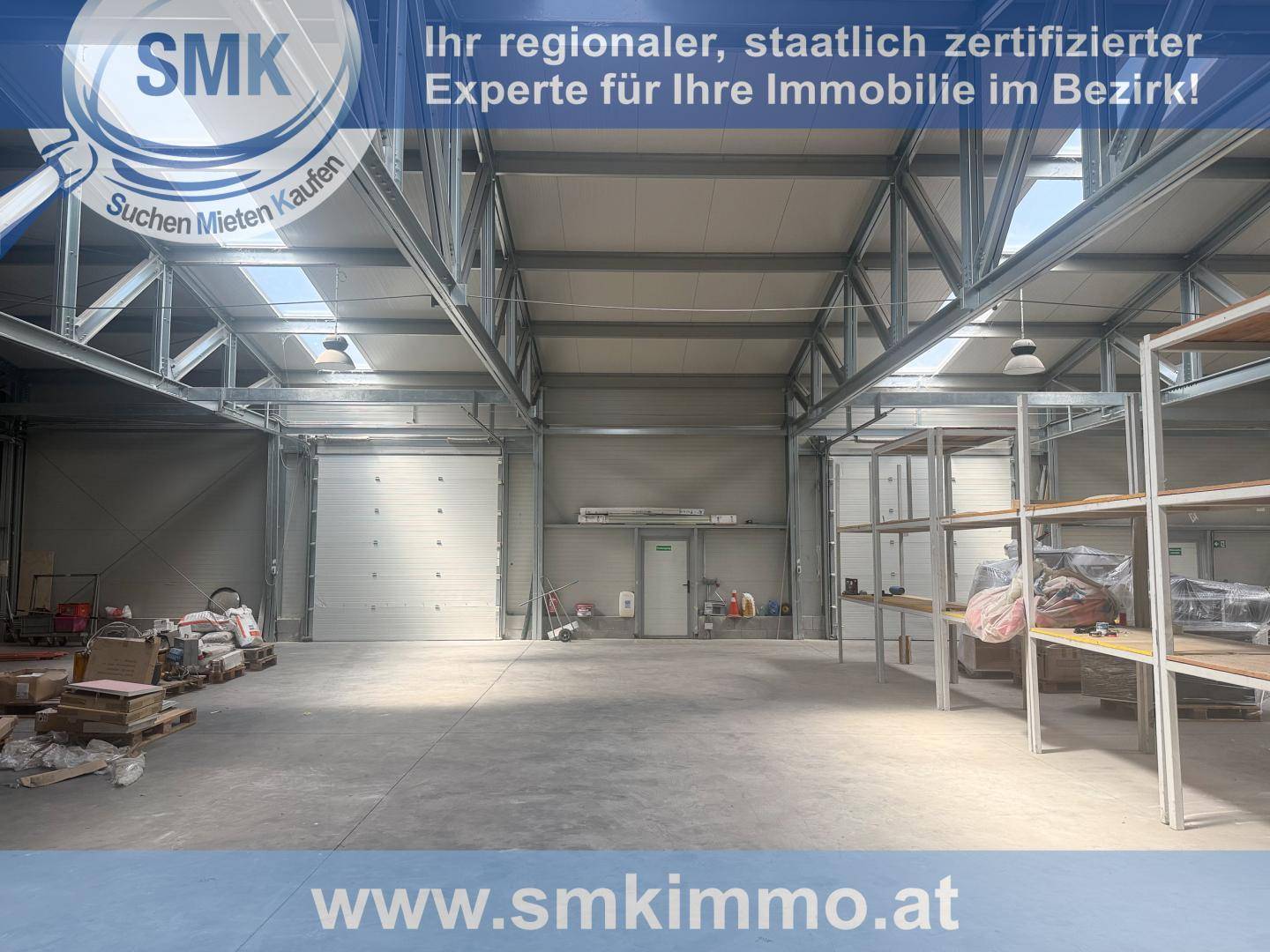 Geräumige Lagerhalle mit hohen Decken, sichtbaren Metallträgern und einem großen Rolltor.