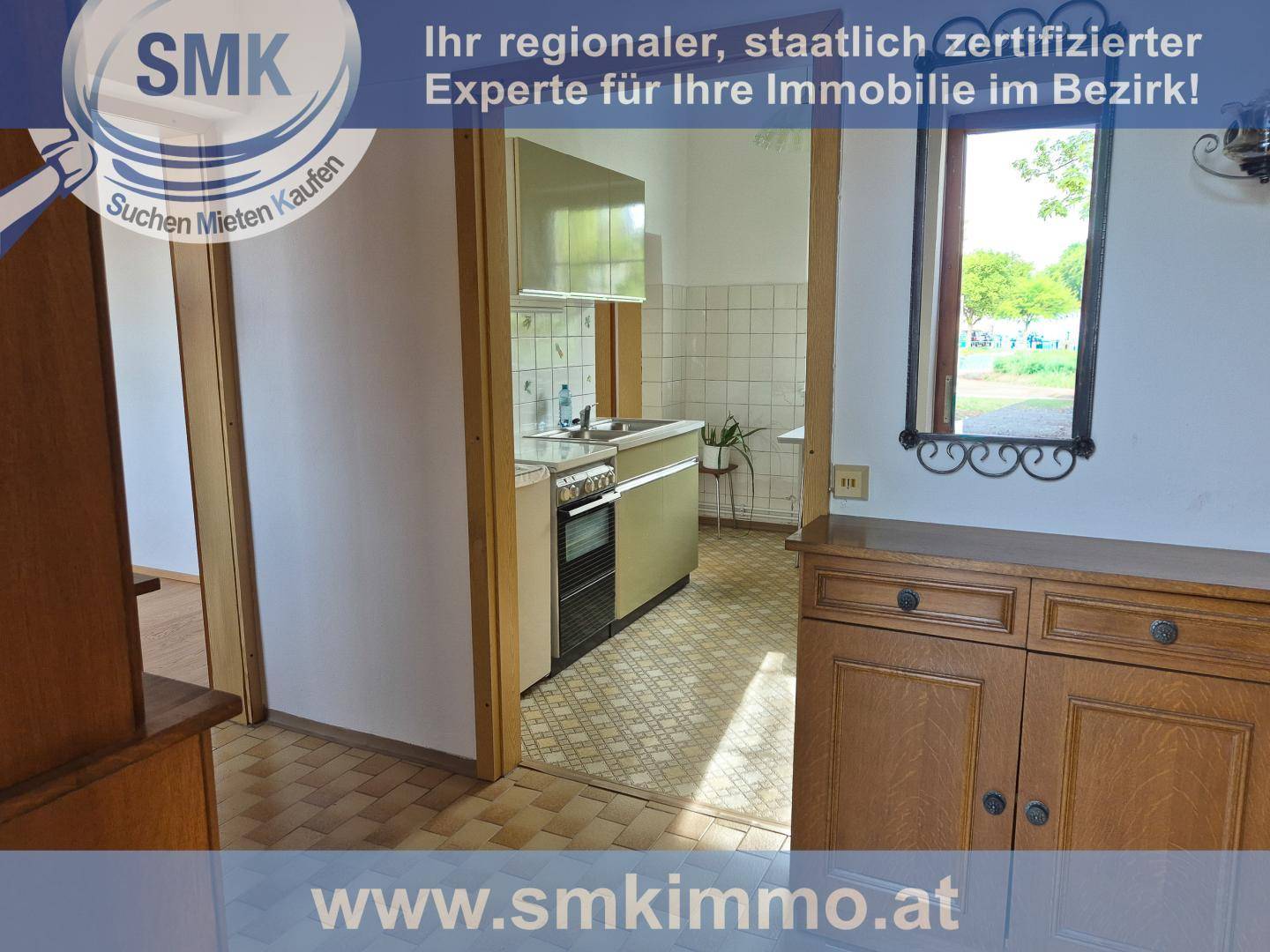 Flur mit Blick in eine Küche im älteren Stil und einem Holzschrank.