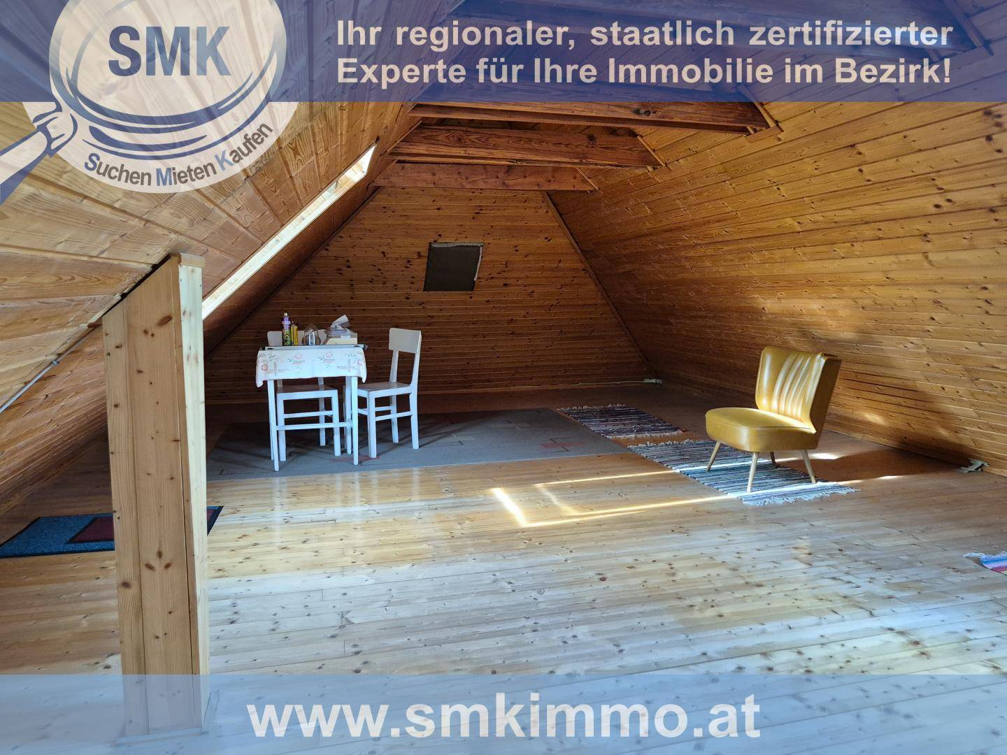 Heller Dachboden mit Holzverkleidung, kleinem Tisch und Blick durch ein Dachfenster.