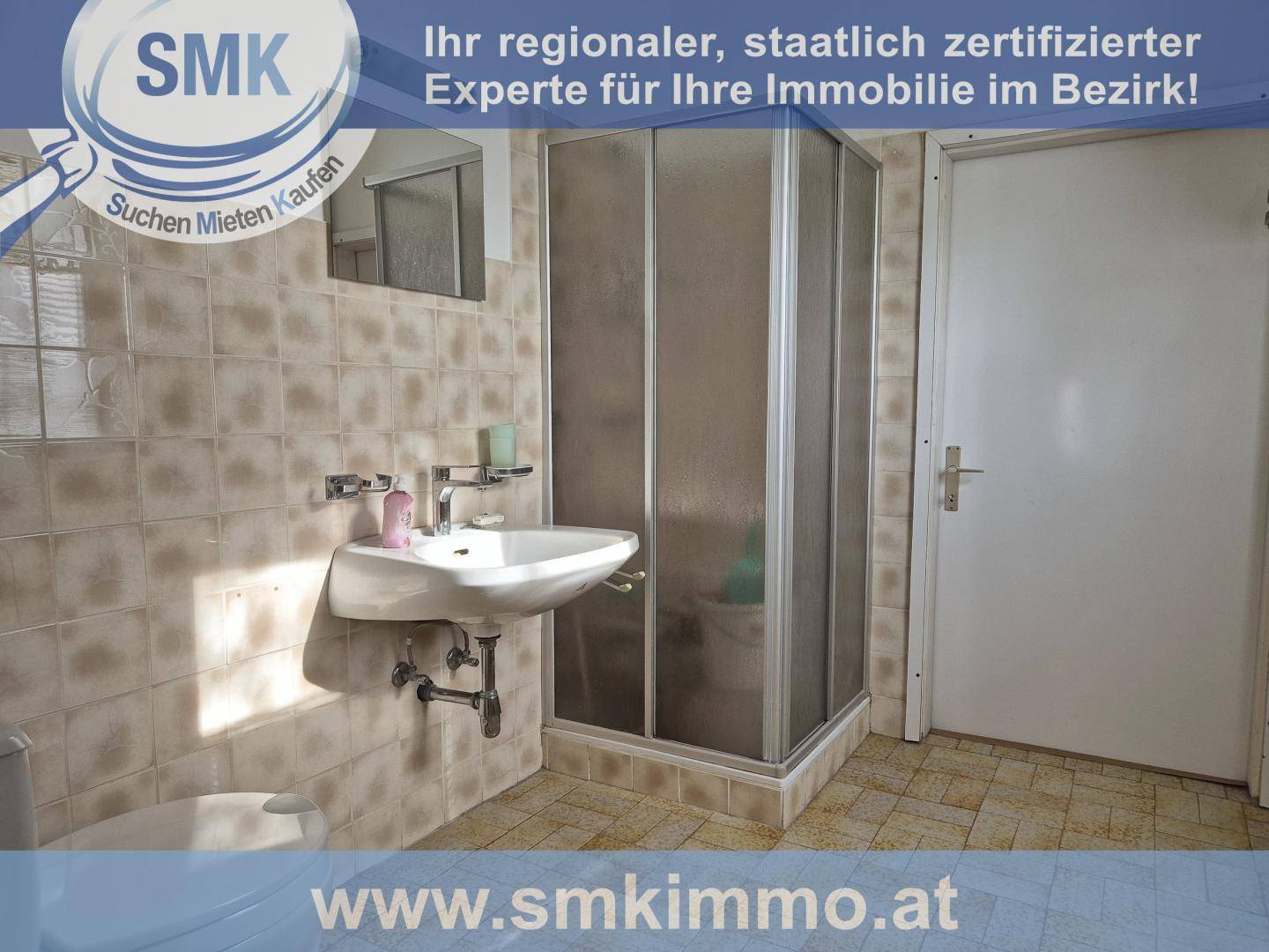 Badezimmer mit beigefarbenen Fliesen, Waschbecken und einer Duschkabine.