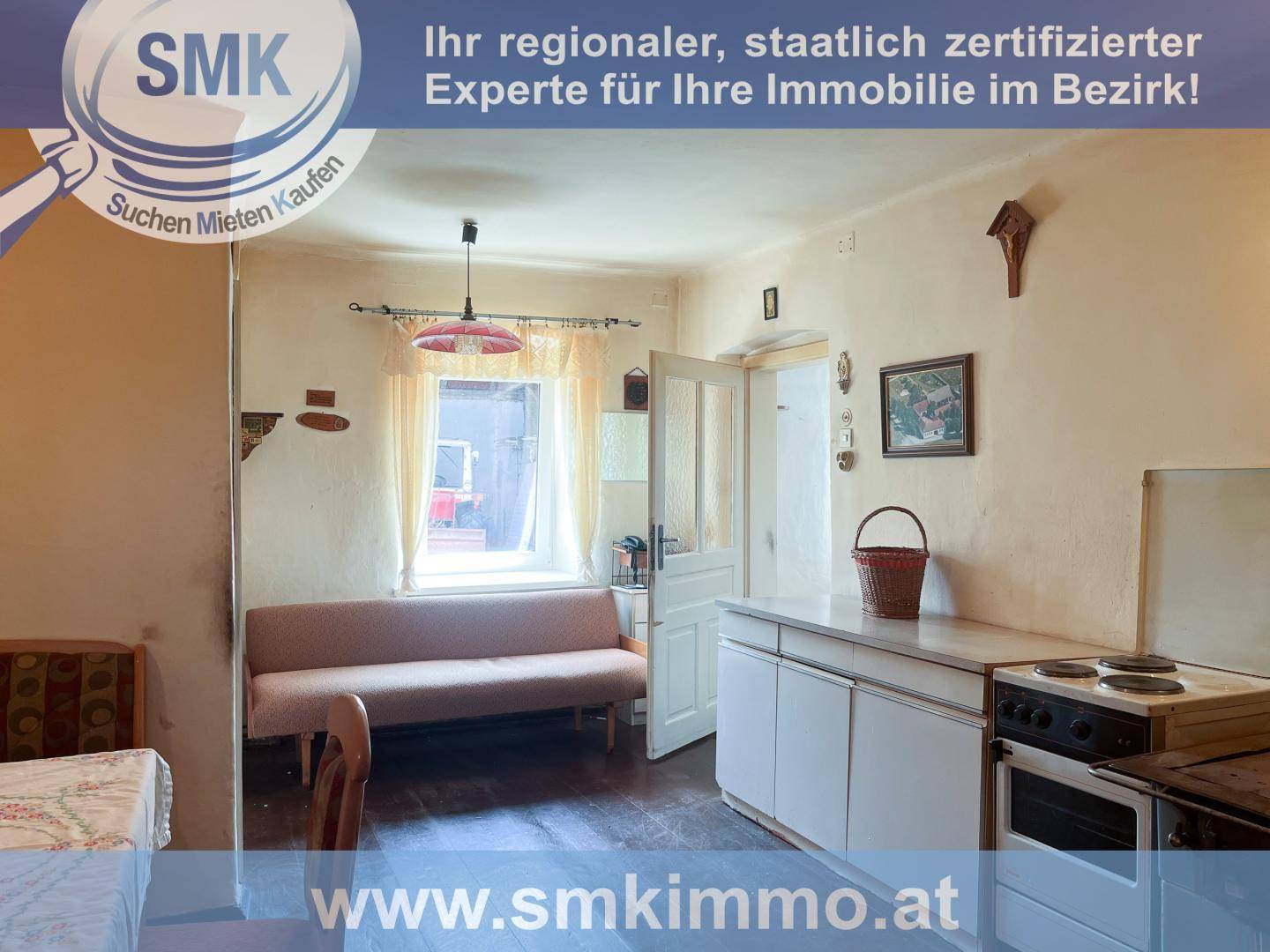 Einfache Küche mit einem Fenster, einer kleinen Couch und einem traditionellen Herd.