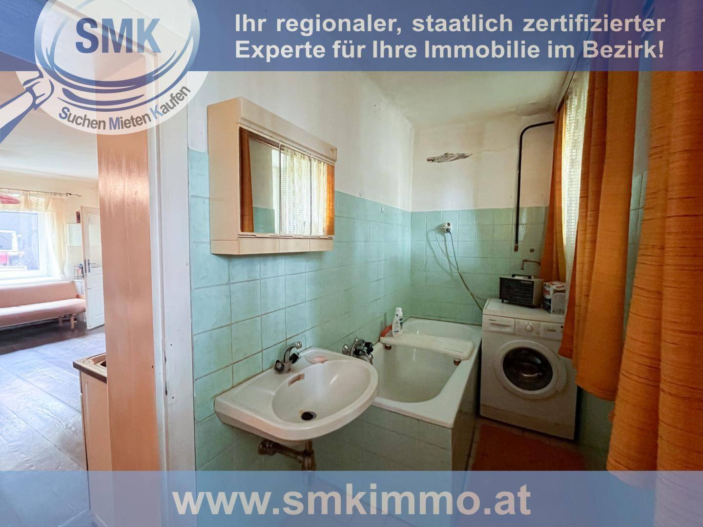 Veraltetes Badezimmer mit hellblauen Fliesen, Badewanne, Waschbecken und Waschmaschine.