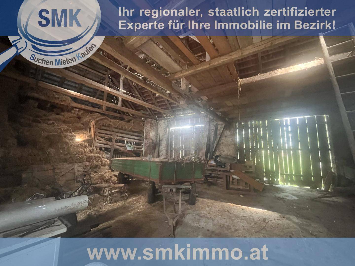 Innenansicht einer Scheune mit Heuballen und sichtbaren Holzkonstruktionen.