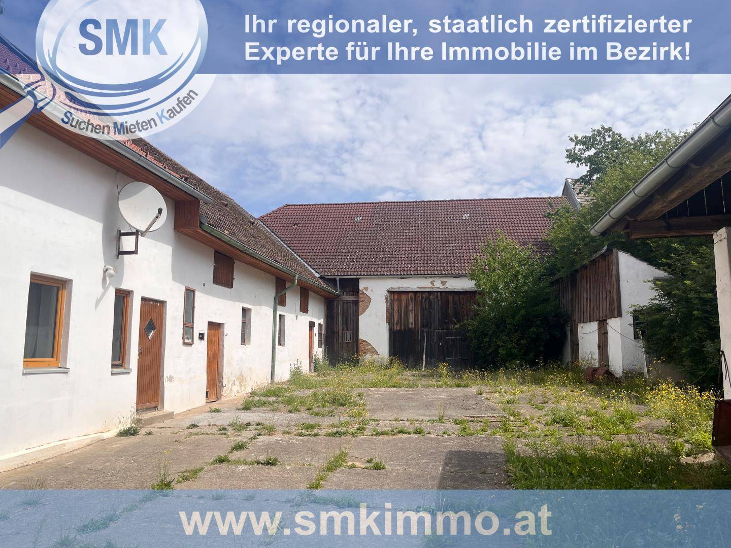 Alter Innenhof mit mehreren ländlichen Gebäuden und Holztüren, umgeben von Gras und Unkraut.