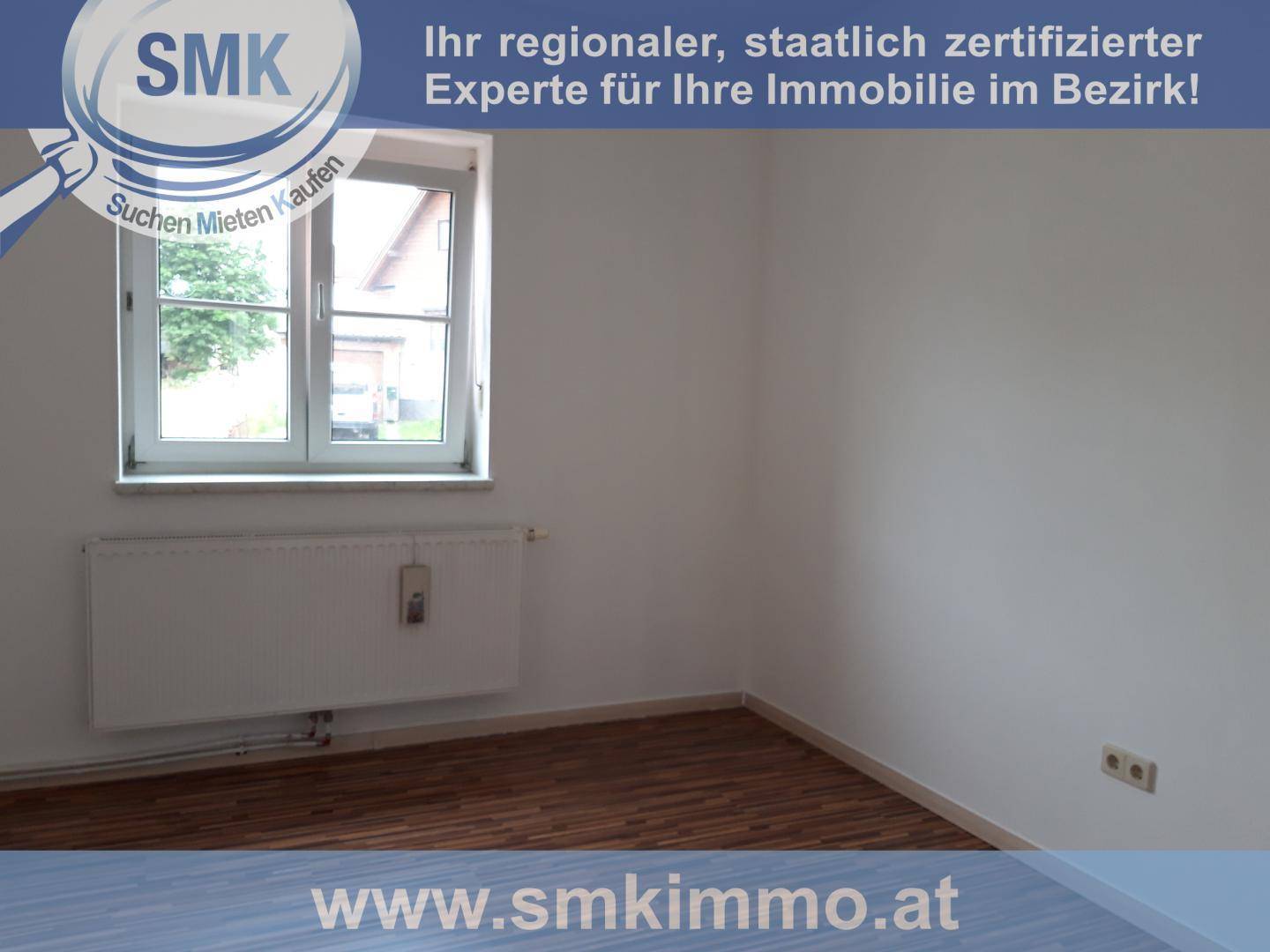 Helles Schlafzimmer mit Laminatboden, weiß gestrichenen Wänden und einem Fenster.