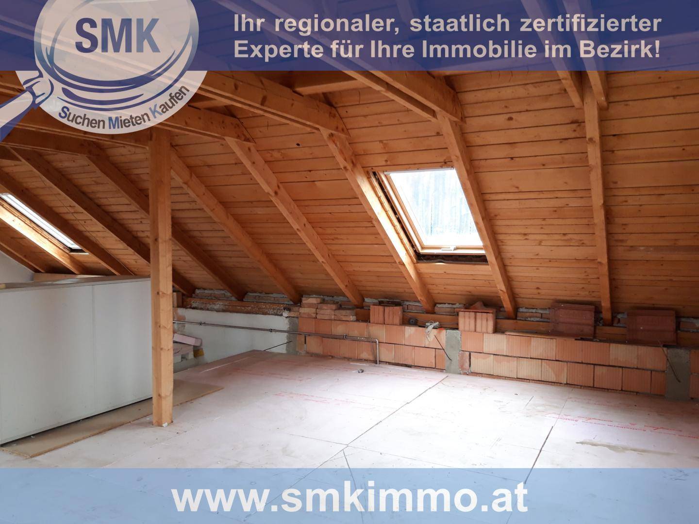 Großer Dachboden mit freiliegenden Holzbalken, Ziegelwänden und einem Dachfenster.