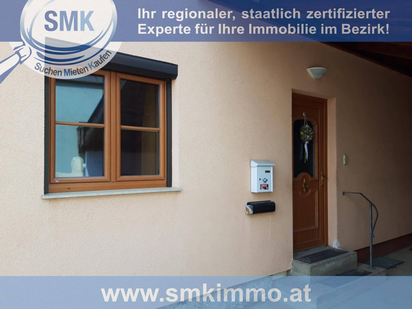 Hauseingang mit Holztür, Fenster mit Rollladen und einem Briefkasten an der Wand.
