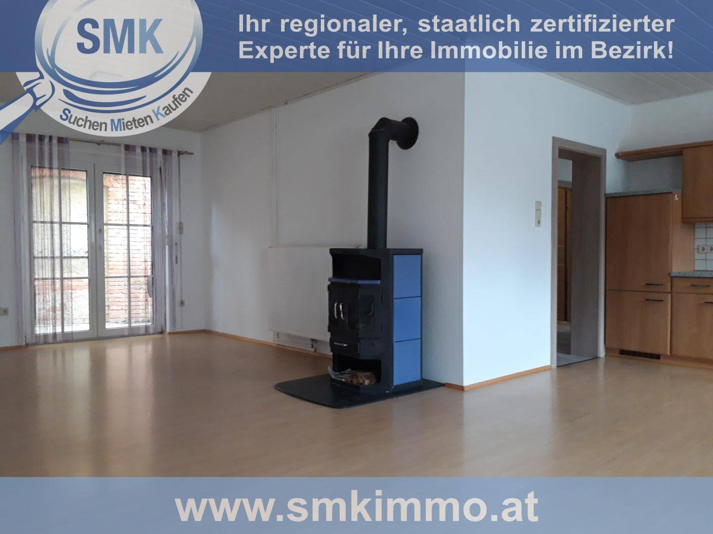 Geräumiger Wohnbereich mit Kaminofen, Laminatboden und offenem Übergang zur Küche.