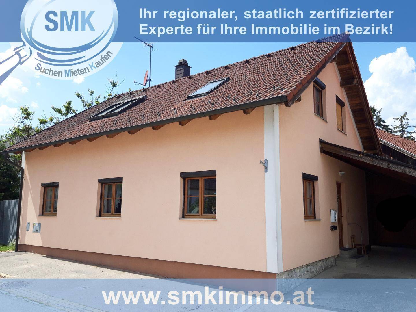 Ansicht des Einfamilienhauses mit beiger Fassade, braunen Fenstern und Satteldach.