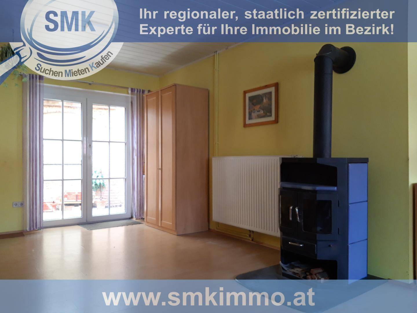 Heller Wohnraum mit Holzboden, Kaminofen und Zugang zu einem Außenbereich durch Glastüren.