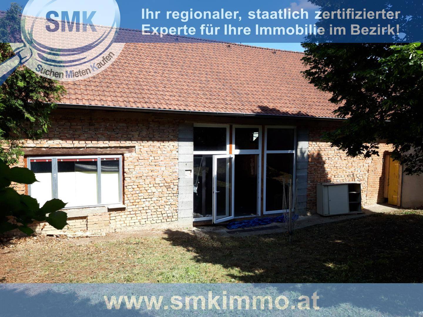 Außenansicht eines Scheunengebäudes mit Ziegelwänden und großen Fensteröffnungen.