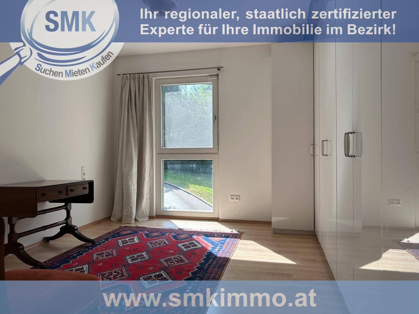 Schlafzimmer mit Fenster, Einbauschrank und Teppich auf Holzboden.