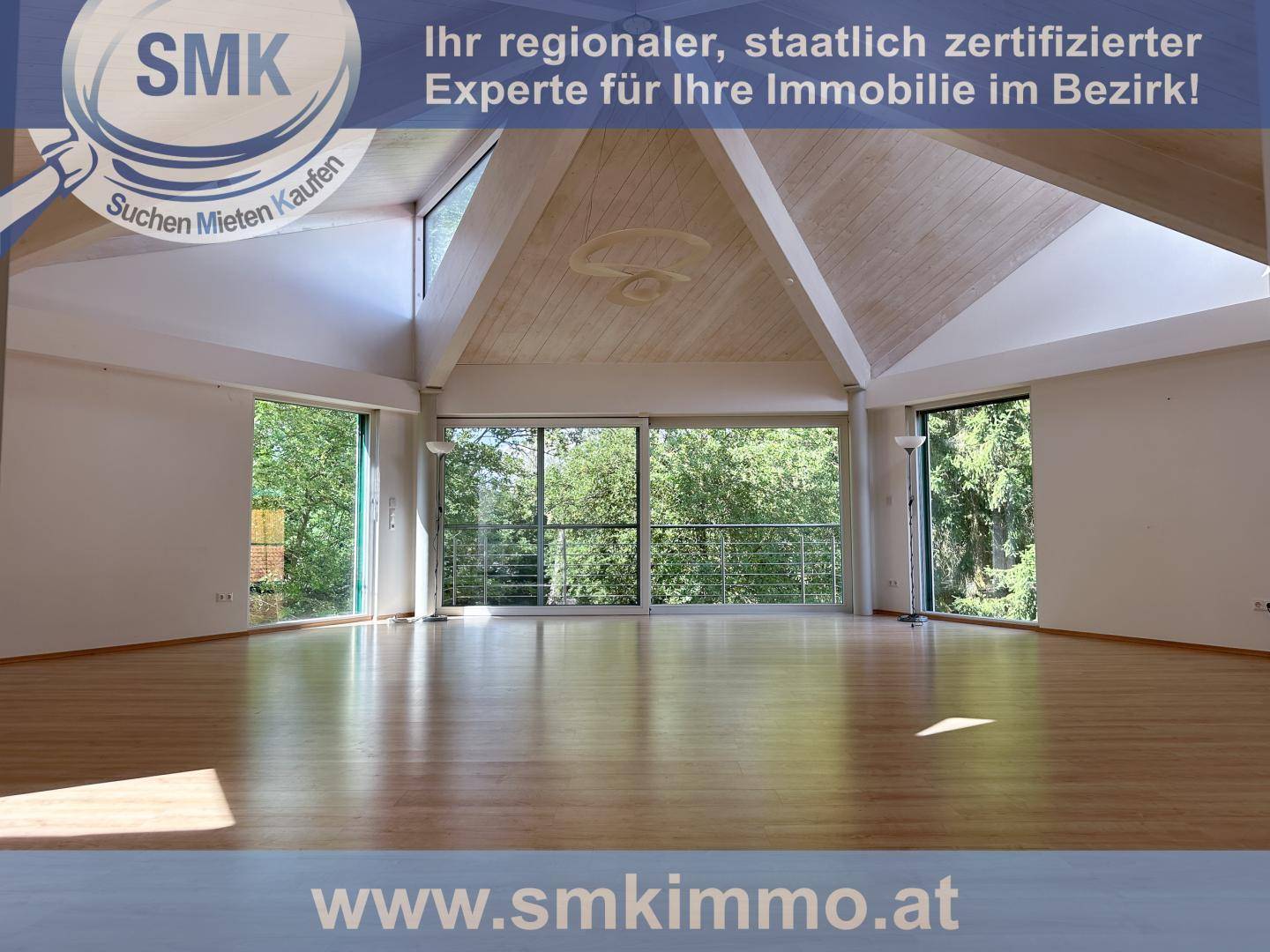 Geräumiges Wohnzimmer mit hohen, gewölbten Decken und großen Fenstern mit Waldblick.