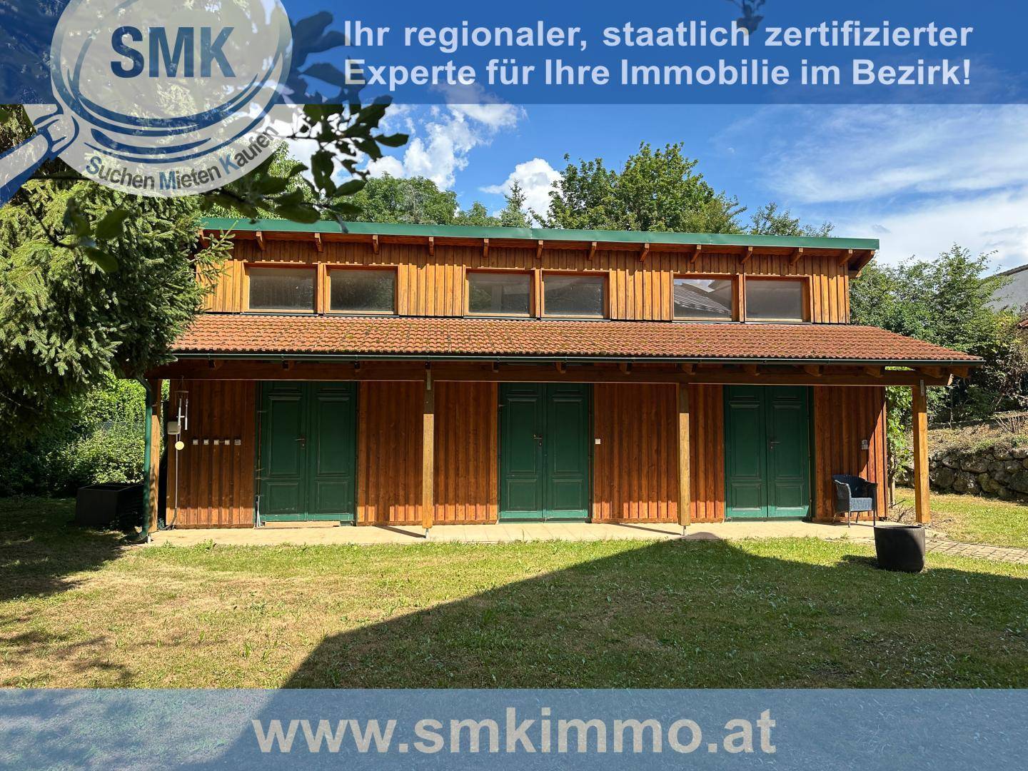 Holzgebäude mit mehreren grünen Türen und Fenstern, umgeben von Rasen.