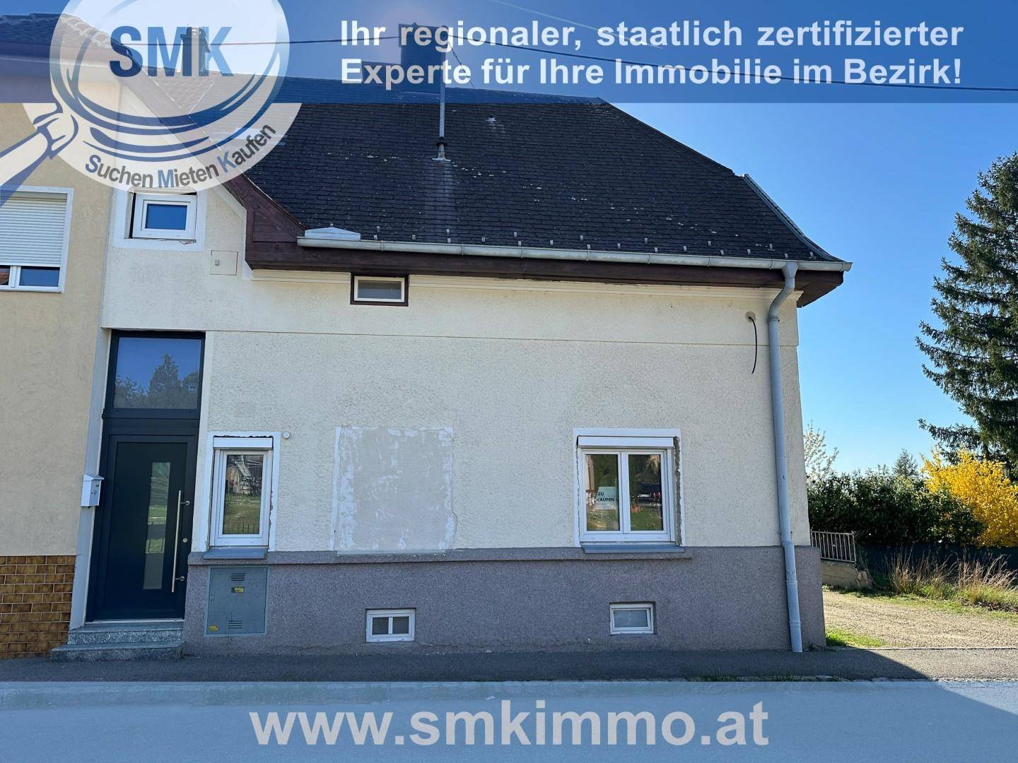 Vorderansicht eines Hauses mit Eingangstür und Fenstern, teilweise renoviert.