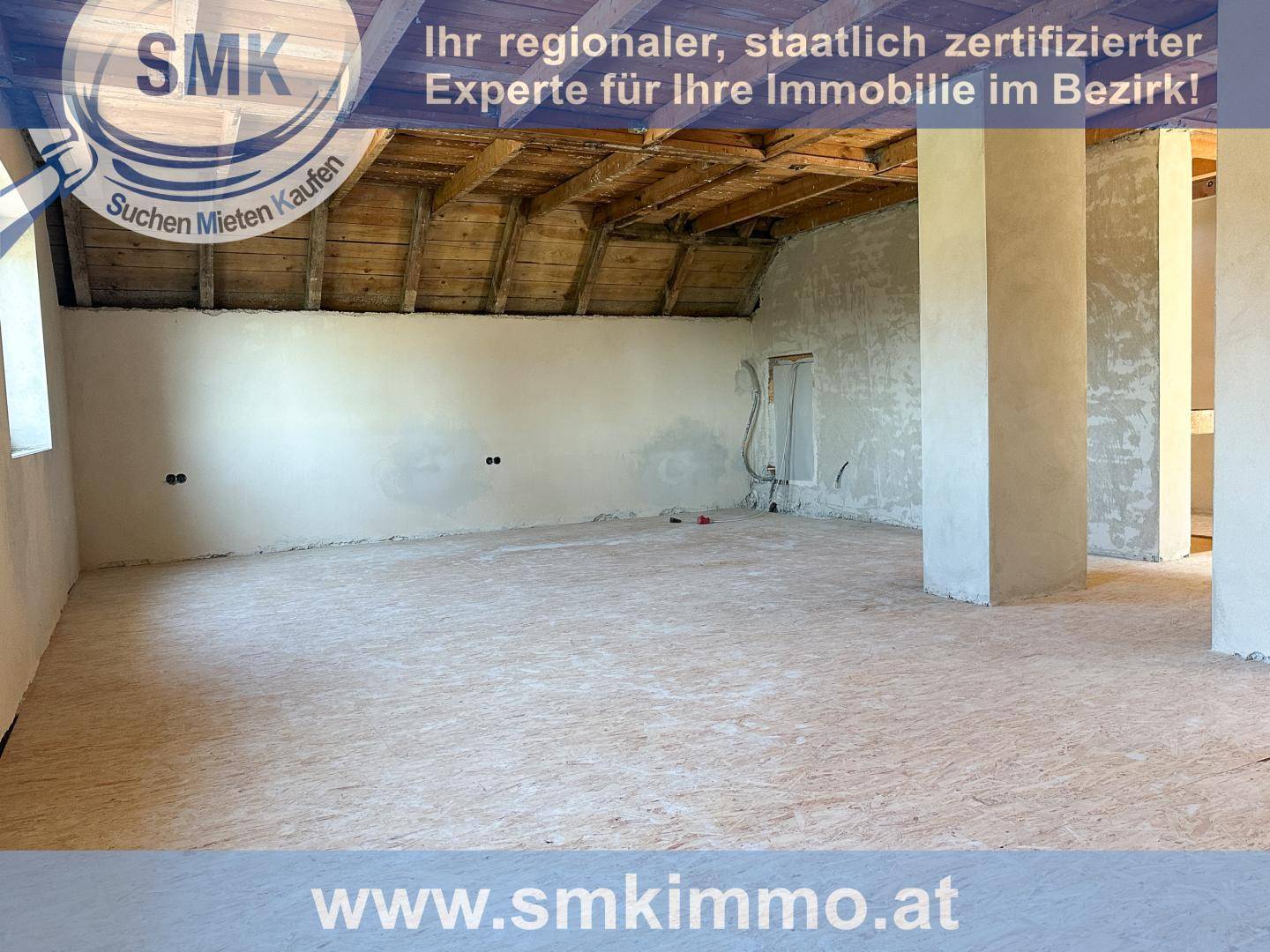 Geräumiger Dachboden im Rohbau mit sichtbaren Holzbalken und Betonboden.