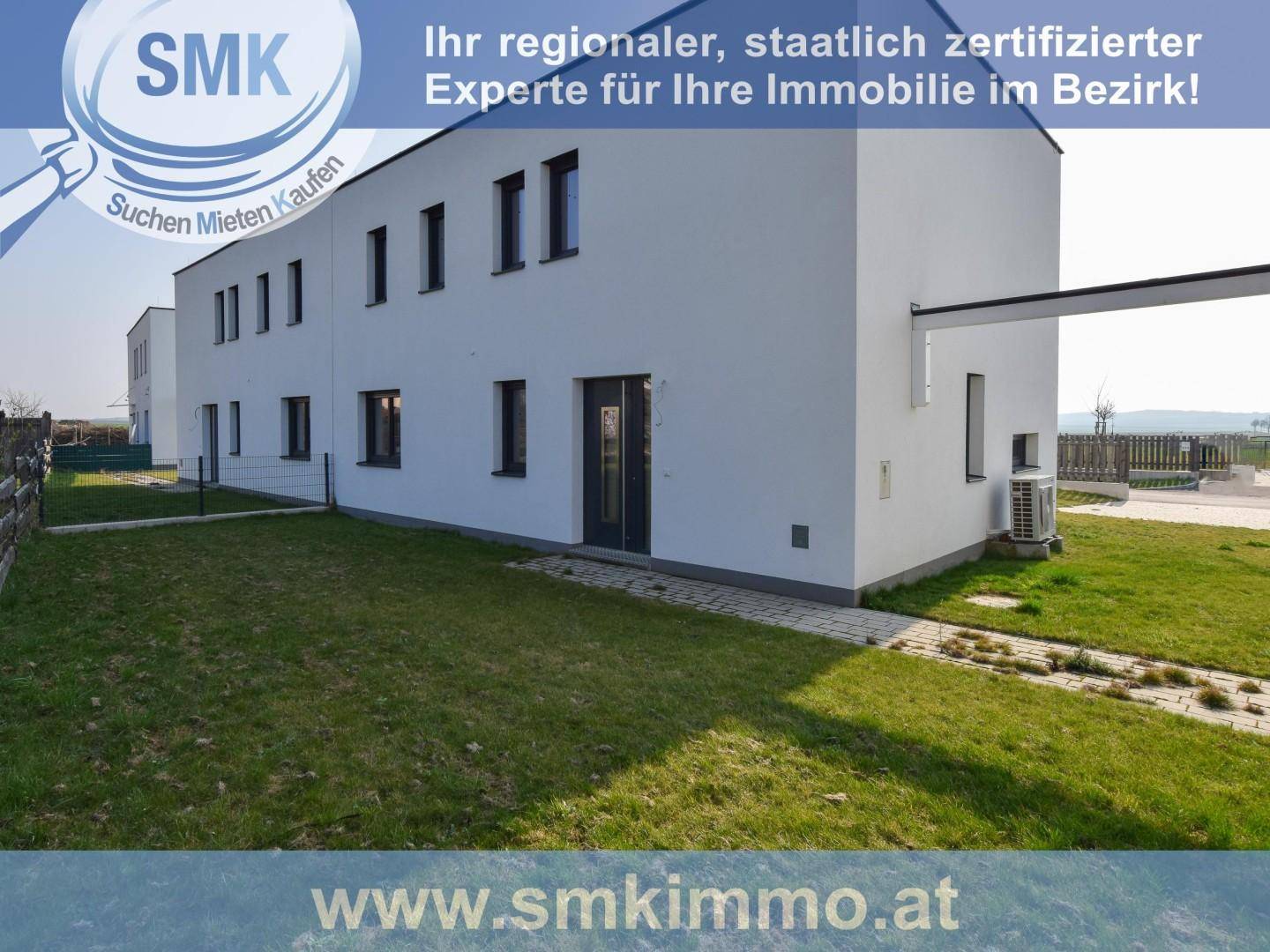 Seitenansicht eines modernen Reihenhauses mit weißer Fassade und kleinem Gartenbereich.