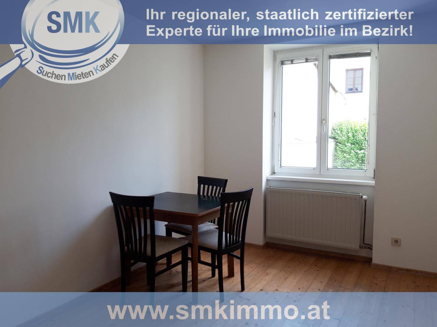 Essbereich mit kleinem Holztisch und Stühlen, Holzboden und einem Fenster mit Blick nach draußen.