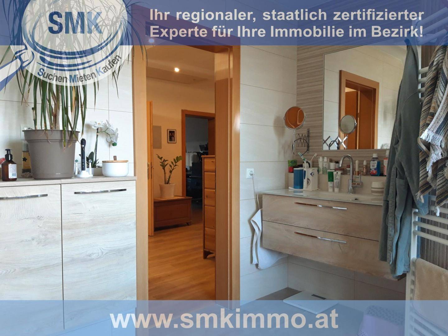 Modernes Badezimmer mit Waschtisch, großem Spiegel und hellem Fliesenboden, gut beleuchtet.