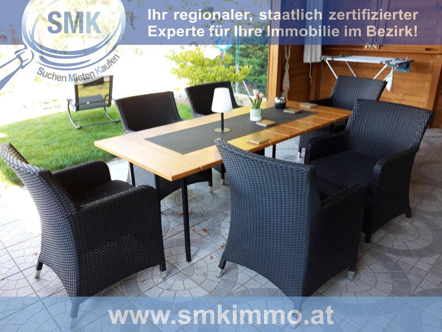 Gemütlicher Essbereich im Freien mit Rattanmöbeln und Holztisch auf einer überdachten Terrasse.