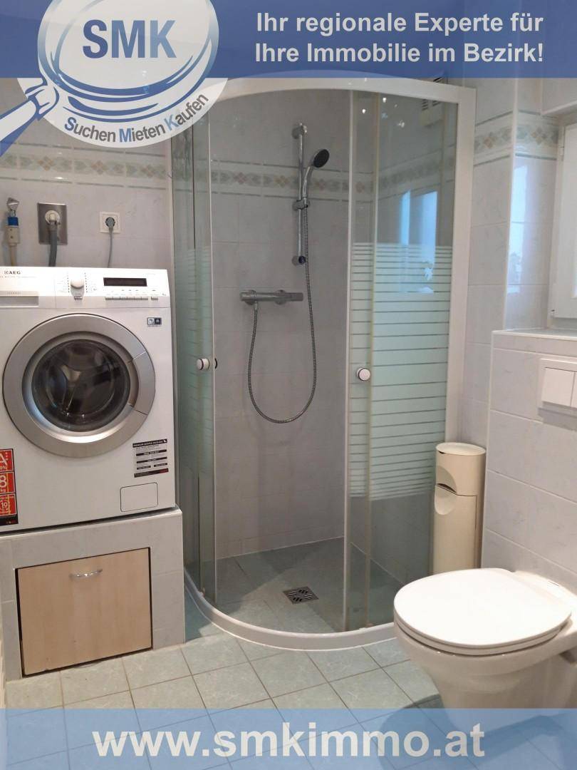 Badezimmer mit Duschkabine, Toilette und Waschmaschine, praktisch und funktional eingerichtet.