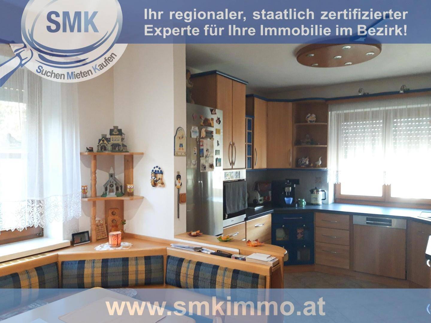 Funktionale Küche mit Holzschränken, integriertem Kühlschrank und einer Essecke am Fenster.