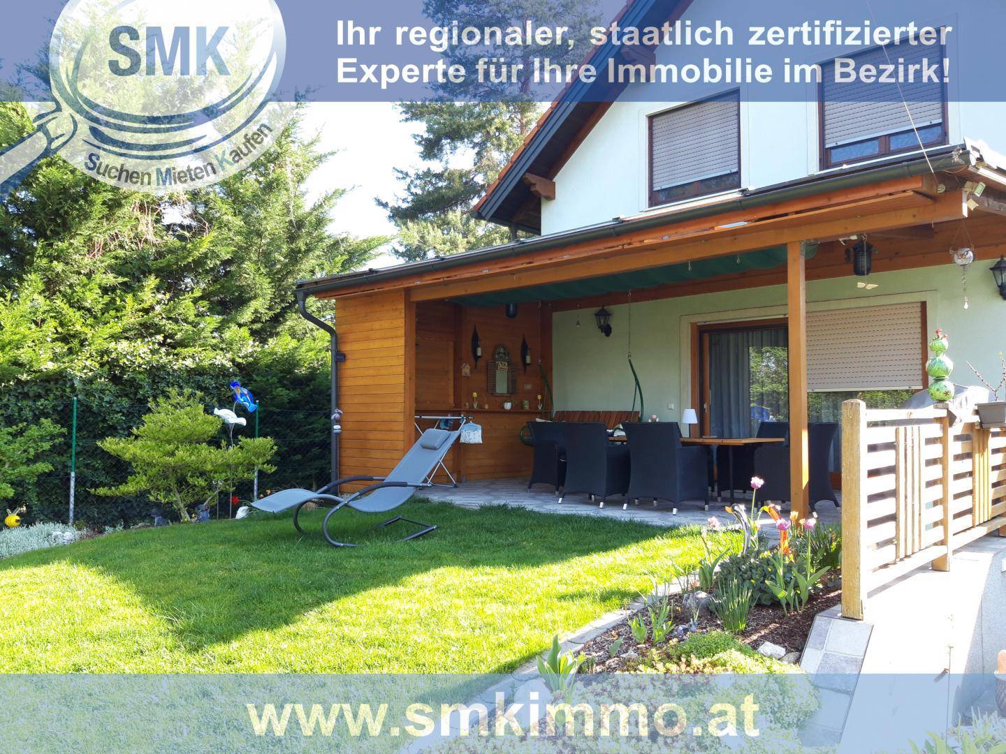 Überdachte Terrasse mit Holzverkleidung, Essbereich und Liegestuhl, angrenzend an den Garten.