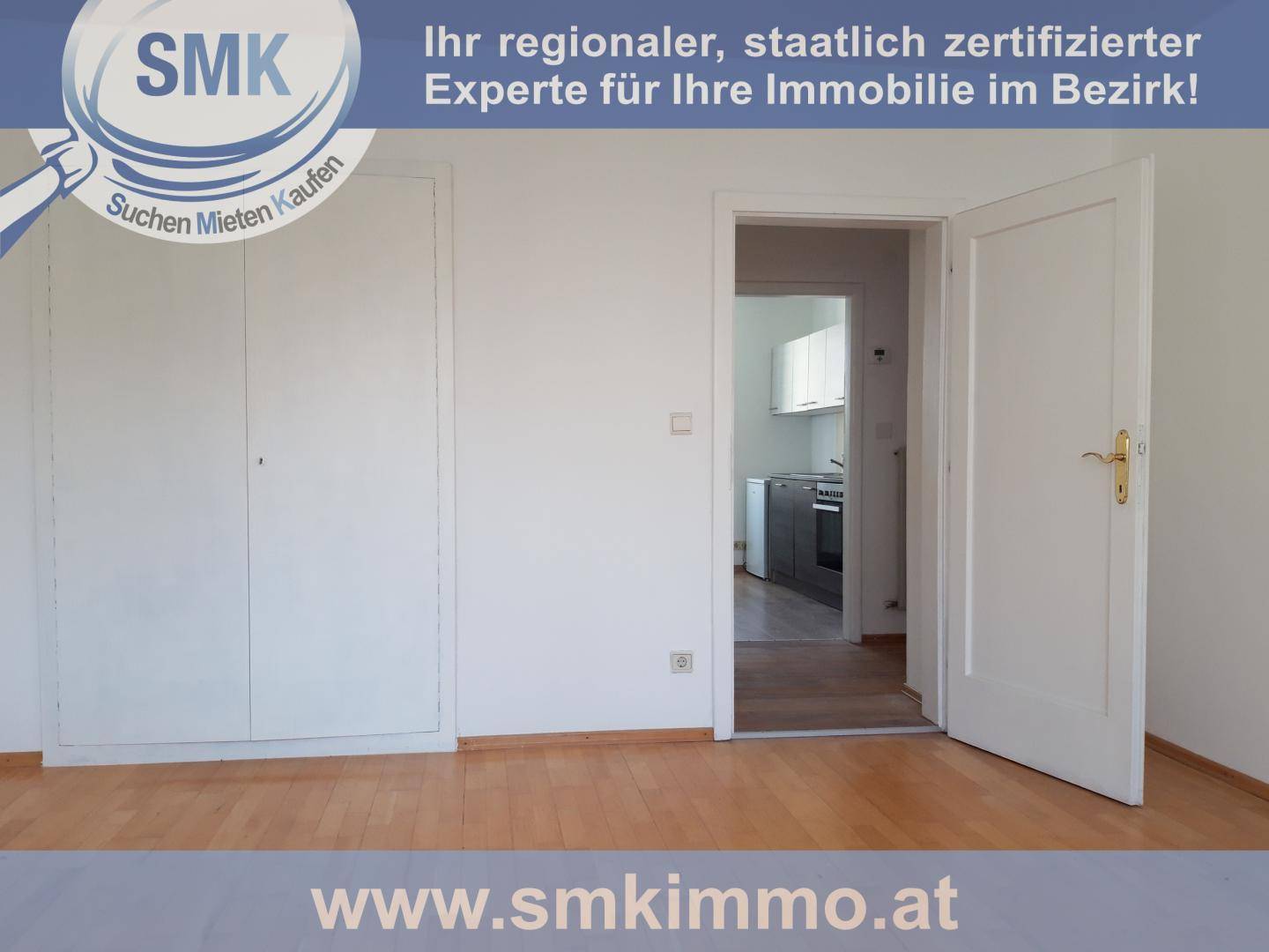 Heller Raum mit Holzboden, weißen Wänden und einem Einbauschrank, der Zugang zur Küche bietet.