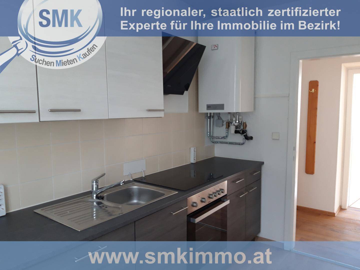 Moderne Küche mit dunklen Unterschränken, hellem Fliesenspiegel und integriertem Kochfeld mit Dunstabzugshaube.