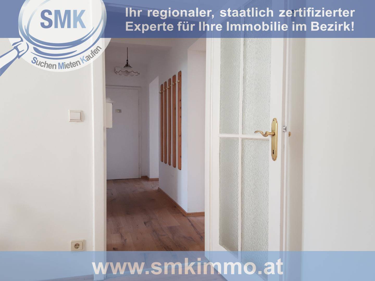 Heller Flur mit Holzboden und einer weißen Tür mit Glaseinsatz, die zu weiteren Räumen führt.