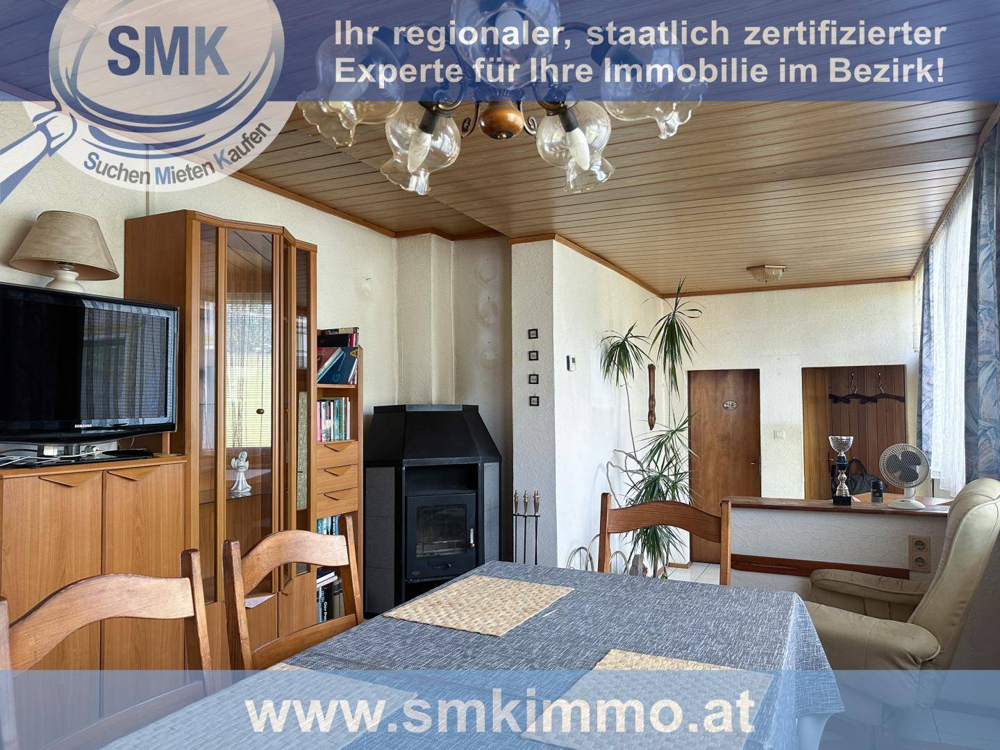 Wohn- und Essbereich mit Holztäfelung, Kaminofen und traditioneller Einrichtung.
